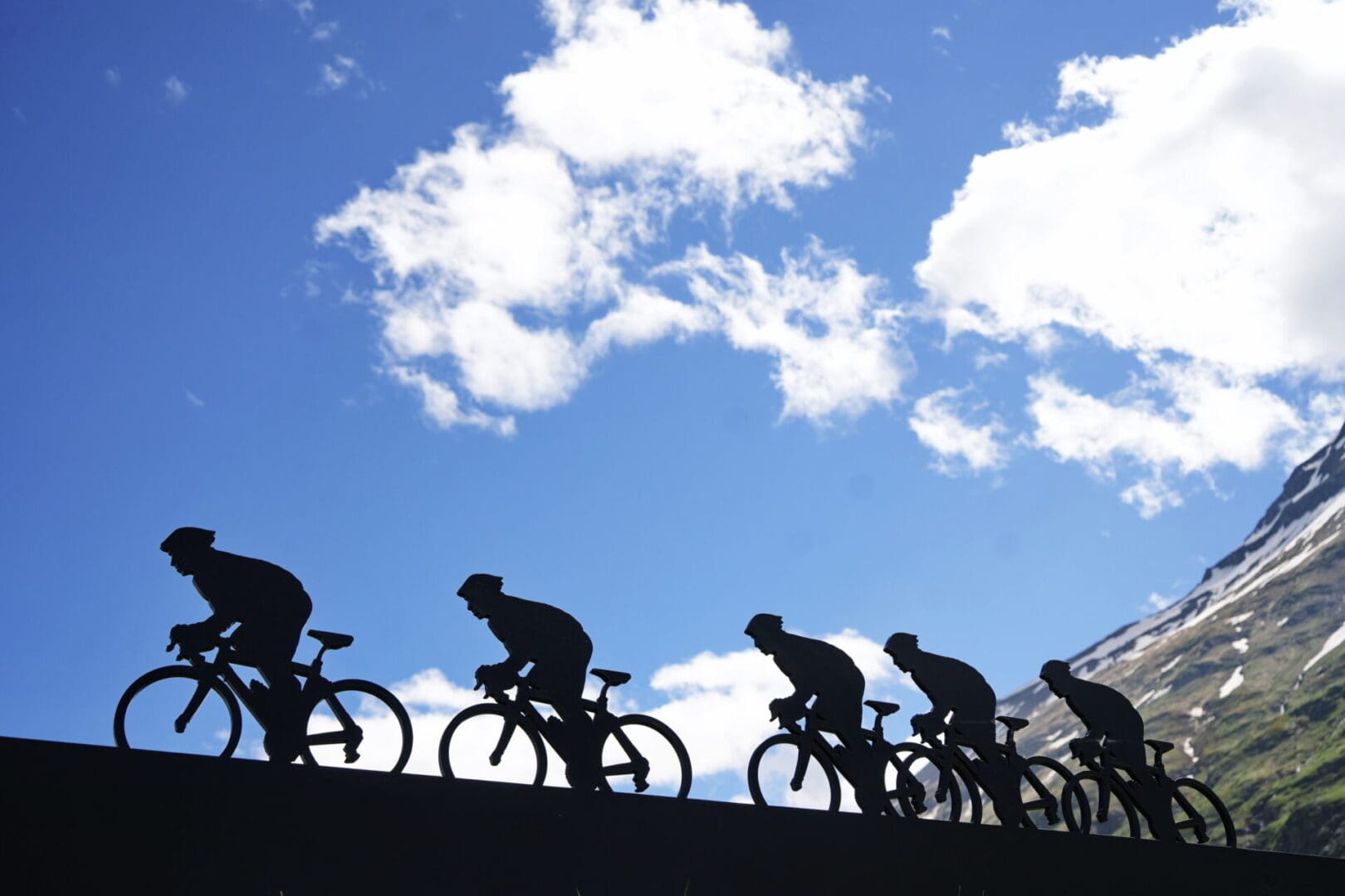 Silhouettes of cyclists against a cloudy sky.